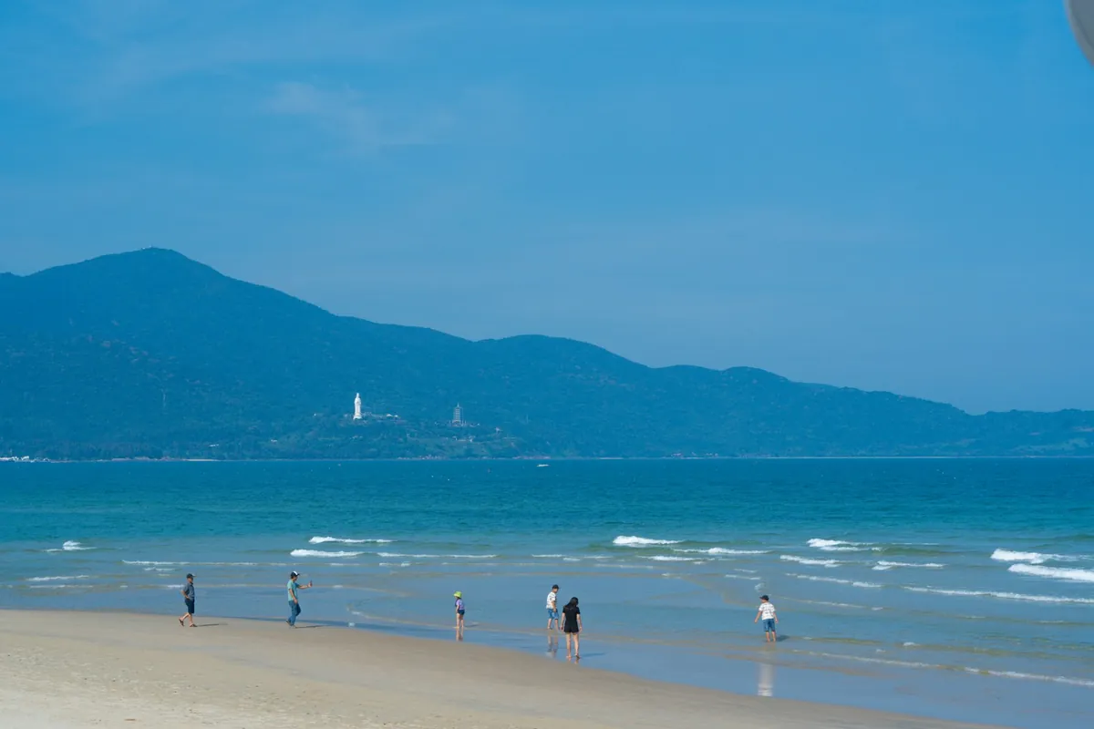 산이 보이는 미케 비치에서 해변을 즐기는 사람들